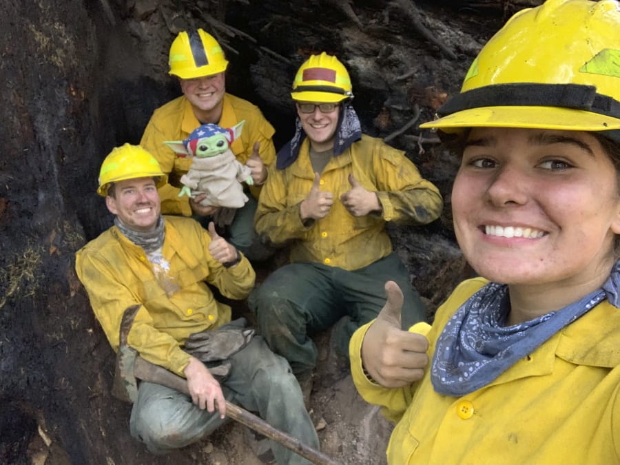 Lucas Galloway, from left, Jaebyn Drake, Rhett Schieder and Audrey Wilcox pose for a selfie with Baby Yoda on Sept. 20 while fighting the Holiday Farm Fire in Blue River, Ore. Beleaguered firefighters in the western United States have a new force on their side: Baby Yoda. In early September, a 5-year-old Oregon boy named Carver and his grandmother delivered a toy version of &quot;The Mandalorian&quot; character to a donation center for firefighters.