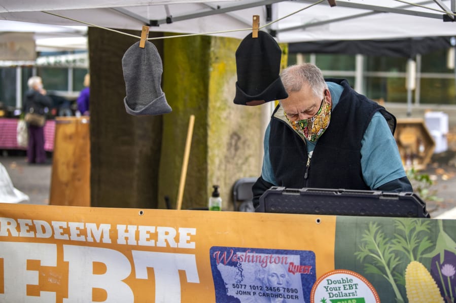 Volunteer Tim Aufmuth processes an Electronic Benefits Transfer card Saturday at the Vancouver Farmers Market's information booth. Customers can redeem their food benefits at the information booth and get a $20 match for fresh fruits and vegetables purchased at the market through the SNAP Market Match program.