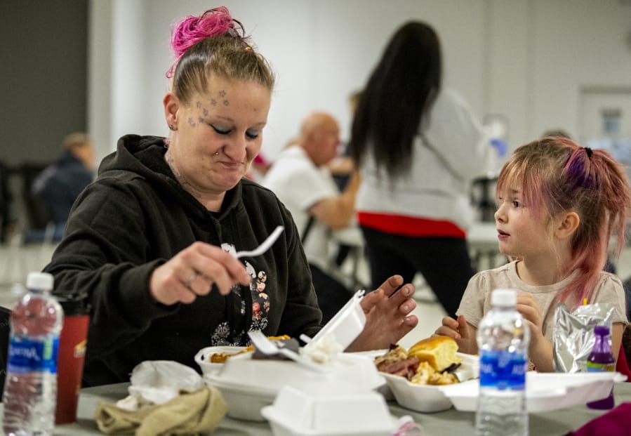 Ashley Green and her daughter, Jordiyn, 7, enjoy a Thanksgiving meal catered by Daddy D's BBQ on Saturday at Living Hope Church. Green has been coming to Living Hope for eight years, and the church provided services that helped Green get out of homelessness.