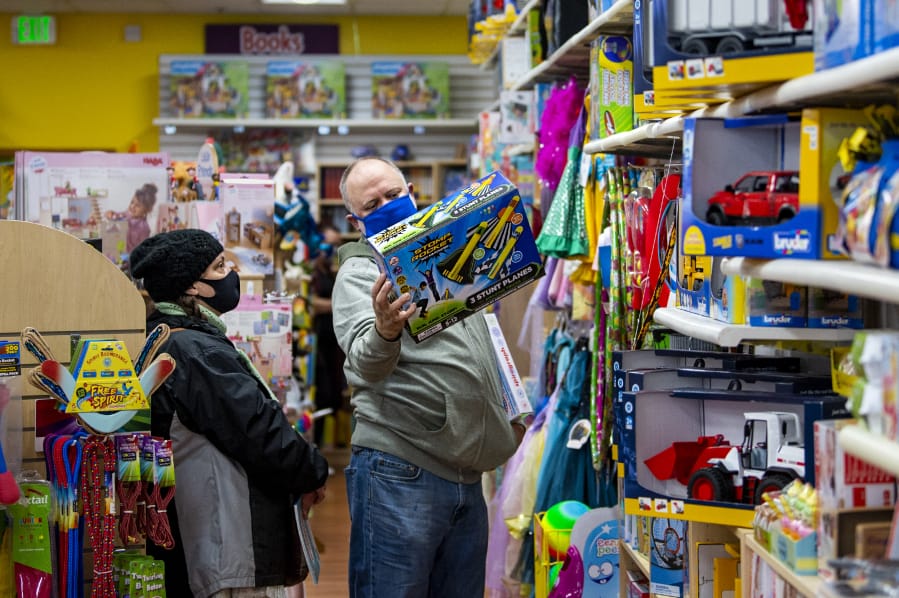 Christine Olsen, left, and Carl Olsen look for Christmas gifts for their kids on Saturday at Kazoodles toy store at Columbia Square in Vancouver. They went to Kazoodles to support small businesses.