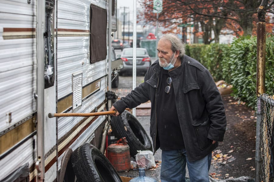 Joe Ingram, a member of the Scofflaw Mitigation Team, taps with his cane to rouse anyone inside this RV behind a Jack in the Box restaurant on First Avenue South in Seattle.