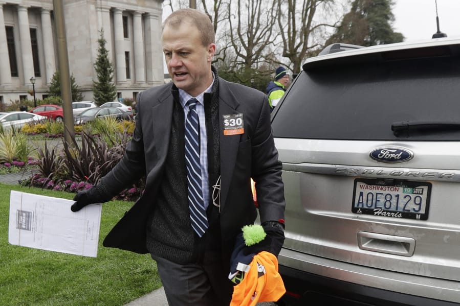 Initiative activist Tim Eyman, who was also running as an independent for Washington governor, carries a clipboard as he walks next to his expired car registration tabs Jan. 13 before attending a rally on the first day of the 2020 session of the Washington legislature at the Capitol in Olympia. (Ted S.