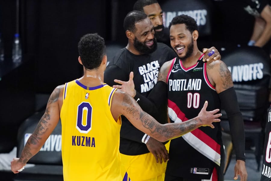 Los Angeles Lakers' Kyle Kuzma (0) and LeBron James, center, greet Portland Trail Blazers' Carmelo Anthony (00) after an NBA basketball first round playoff game Saturday, Aug. 29, 2020, in Lake Buena Vista, Fla. The Lakers won 131-122 to win the series 4-1.