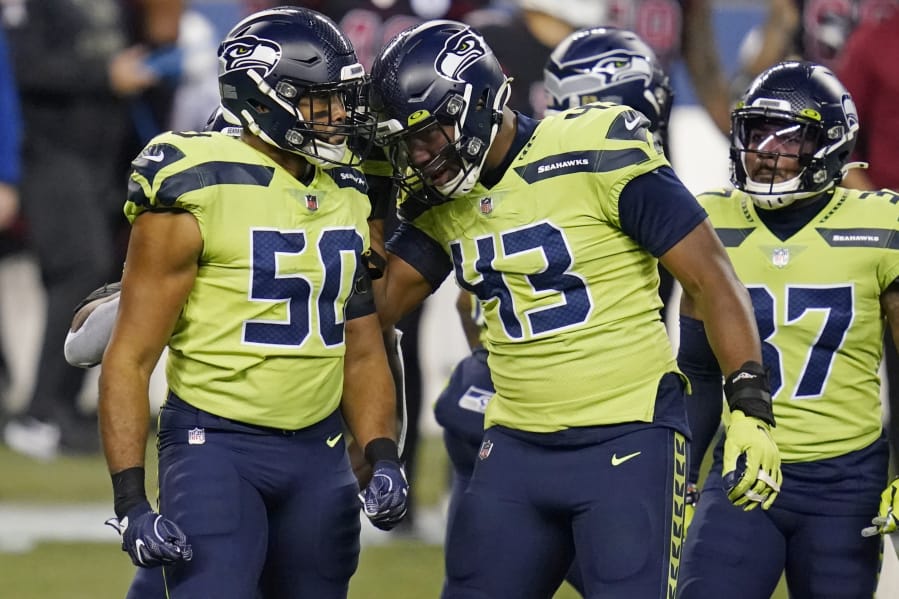 Seattle Seahawks outside linebacker K.J. Wright (50) and defensive end Carlos Dunlap (43) celebrate after a play against the Arizona Cardinals during the first half of an NFL football game, Thursday, Nov. 19, 2020, in Seattle.