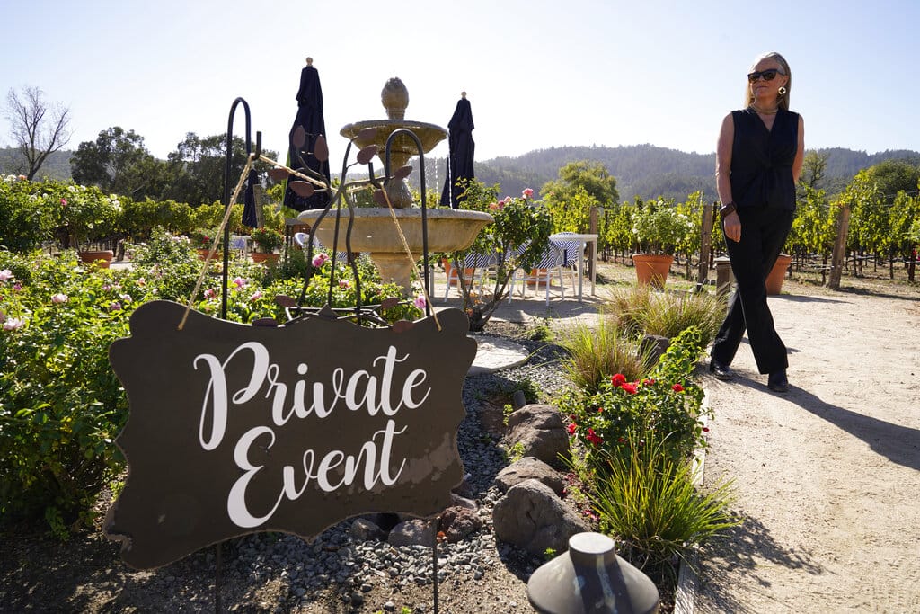 Event planner Janice Twomey looks over a garden area where weddings were often held at Brix Napa Valley near Oakville, Calif., on Thursday, Oct. 15, 2020.  In three of the past four years, major wildfires driven by a changing climate have devastated parts of the world-class region, leaving little doubt that it's vulnerable to smoke, flames and blackouts during the fall.