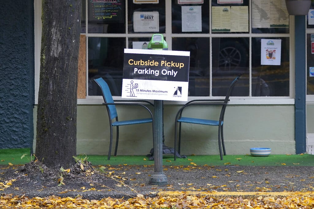A sign for curbside pickup is shown outside the Cascadia Grill, Sunday, Nov. 15, 2020, in downtown Olympia. (AP Photo/Ted S.