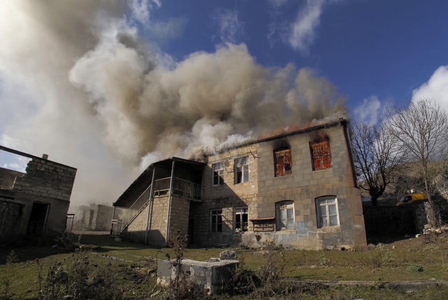 Smoke rises from a burning house in an area once occupied by Armenian forces but soon to be turned over to Azerbaijan, in Karvachar, the separatist region of Nagorno-Karabakh, on Friday, Nov. 13, 2020. Under an agreement ending weeks of intense fighting over the Nagorno-Karabakh region, some Armenian-held territories adjacent to the region are passing to Azerbaijan.