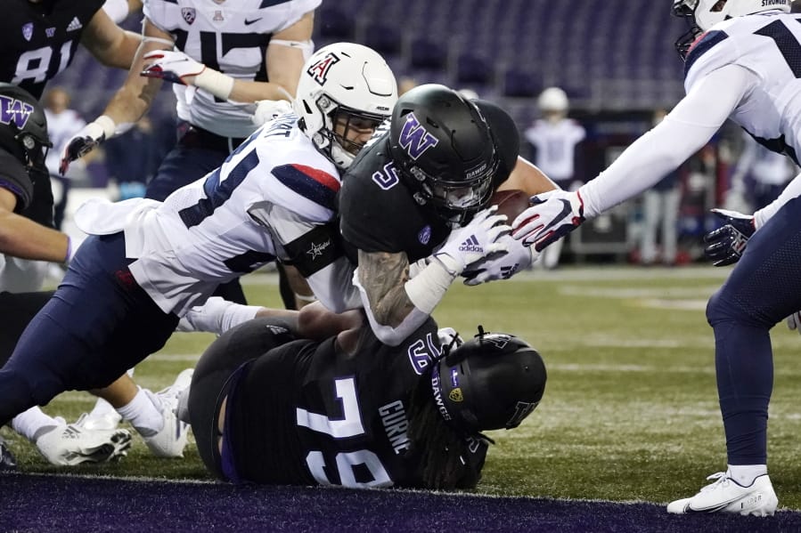 Washington&#039;s Sean McGrew (5) dives over teammate Victor Curne (79) to score against Arizona during the first half of an NCAA college football game Saturday, Nov. 21, 2020, in Seattle.