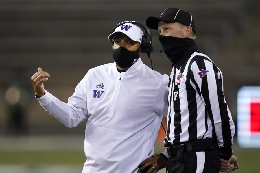 Washington coach Jimmy Lake talks with field judge Todd Migchelbrink during the first half of an NCAA college football game Saturday, Nov. 21, 2020, in Seattle.