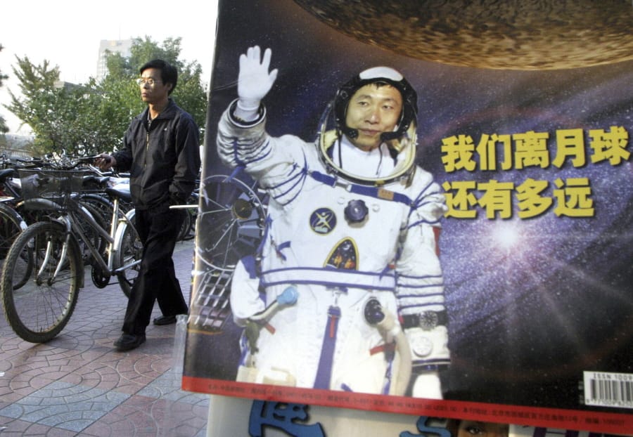 In this photo taken Thursday, Oct 23, 2003, a man pushes his bicycle past the cover of a magazine showing China&#039;s first man in space, Yang Liwei and the Chinese characters for &quot;How far are we from the moon?&quot; at a newsstand in Beijing, China. China&#039;s Nov. 24, 2020, trip to the moon and, presumably, back is the latest milestone in the Asian powerhouse&#039;s slow but steady ascent to the stars.