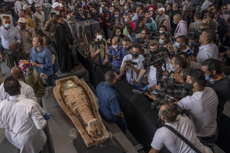 Journalists gather around an ancient sarcophagus more than 2500 years old, discovered in a vast necropolis and Mostafa Waziri, the secretary-general of the Supreme Council of Antiquities, center, in Saqqara, Giza, Egypt, Saturday, Nov. 14, 2020. Egyptian antiquities officials on Saturday announced the discovery of at least 100 ancient coffins, some with mummies inside, and around 40 gilded statues south of Cairo.