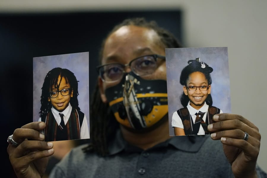FILE - In this Tuesday, Oct. 27, 2020, file photo, Sheldon Smith, center, holds the photographs of his children Deshawn Smith, 11, left, and Trinitee Smith, 13, both suffering from sickle cell anemia, during an Initiative 65 rally in Ridgeland, Miss. Smith and his wife Keishawna Smith believe their children would benefit from medical marijuana treatment for pain management. Initiative 65 would amend the Mississippi Constitution to allow the prescription by a doctor of up to 5 ounces (142 grams) of marijuana per month for people who suffer from more than 20 medical conditions. The state lawmakers are offering a more restrictive measure as an alternative. (AP Photo/Rogelio V.