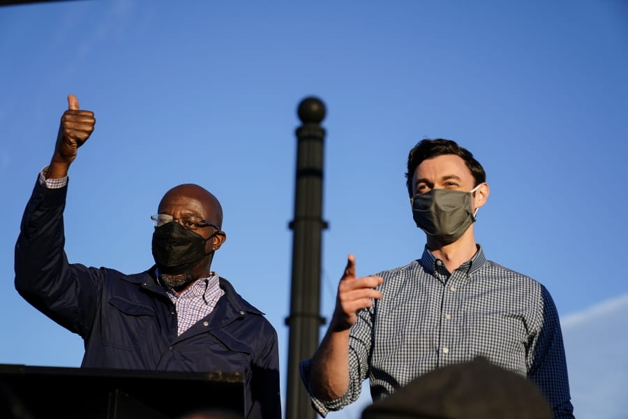 Georgia Democratic candidates for U.S. Senate Raphael Warnock, left, and Jon Ossoff, right, gesture toward a crowd during a campaign rally on Sunday, Nov. 15, 2020, in Marietta, Ga.