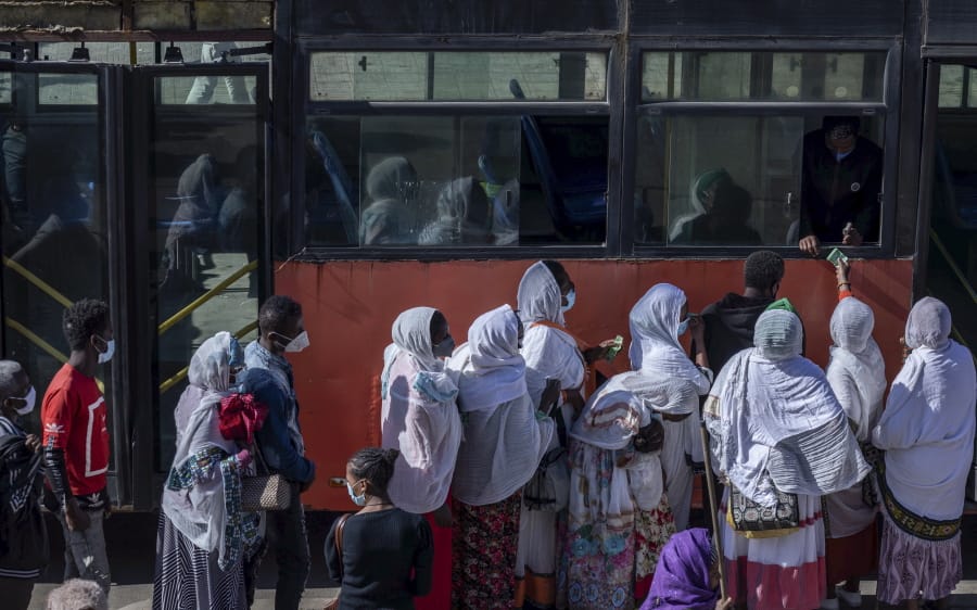 Passengers queue to get on a bus in the capital Addis Ababa, Ethiopia Friday, Nov. 6, 2020.