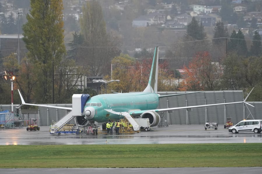 Workers stand near a Boeing 737 Max airplane parked at Renton Municipal Airport, Wednesday, Nov. 18, 2020, next to the Boeing assembly facility in Renton, Wash. where 737 Max airplanes are made. After nearly two years and a pair of deadly crashes, the U.S. Federal Aviation Administration announced Wednesday that the 737 Max has been cleared for flight after regulators around the world grounded the Max in March 2019, after the crash of an Ethiopian Airlines jet. (AP Photo/Ted S.