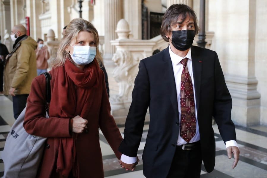 French-American Mark Moogalian, right, and his wife Isabelle arrive at the Thalys attack trial, at the Paris courthouse, Thursday, Nov. 19, 2020. The lawyer for an American who was scheduled to testify about his role in the dramatic capture of an Islamic State operative aboard a high-speed train says his witness has been hospitalized after he flew in to Paris.