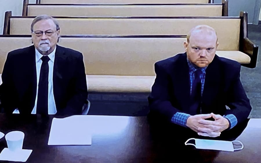 In this image made from video, from left, father and son, Gregory and Travis McMichael, accused in the shooting death of Ahmaud Arbery in Georgia on Feb. 2020, listen via closed circuit tv in the Glynn County Detention center in Brunswick, Ga., on Thursday, Nov. 12, as lawyers argue for bond to be set at the Glynn County courthouse.