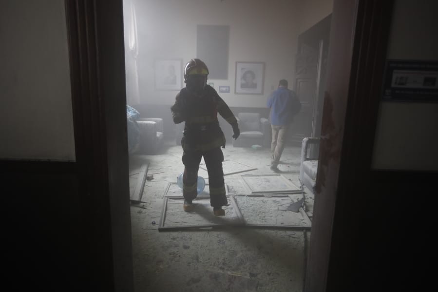 A firefighter walks inside the Congress building after protesters set the building on fire, in Guatemala City, Saturday, Nov. 21, 2020. Hundreds of protesters were protesting in various parts of the country Saturday against Guatemalan President Alejandro Giammattei and members of Congress for the approval of the 2021 budget that reduced funds for education, health and the fight for human rights.