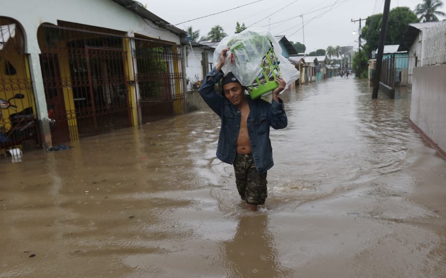 A man walks in knee-deep floodwaters carrying belongings in San Manuel, Honduras, Wednesday, Nov. 4, 2020. Eta weakened from the Category 4 hurricane to a tropical storm after lashing the Caribbean coast for much of Tuesday, its floodwaters isolating already remote communities and setting off deadly landslides.