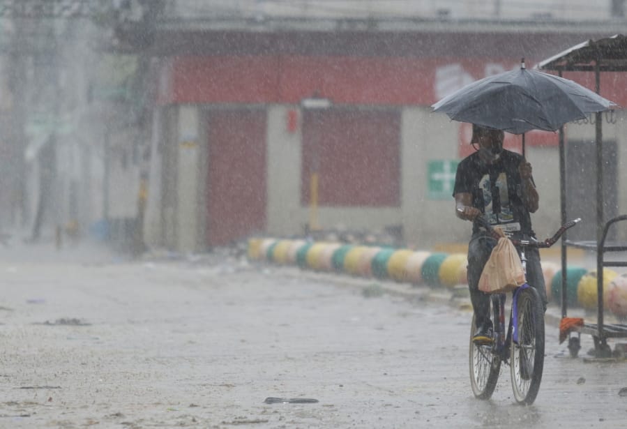 A man rides his bicycle under the rain brought by Hurricane Iota, in La Lima, Honduras, Tuesday, Nov. 17, 2020. Hurricane Iota tore across Nicaragua on Tuesday, hours after roaring ashore as a Category 4 storm along almost exactly the same stretch of the Caribbean coast that was recently devastated by an equally powerful hurricane.