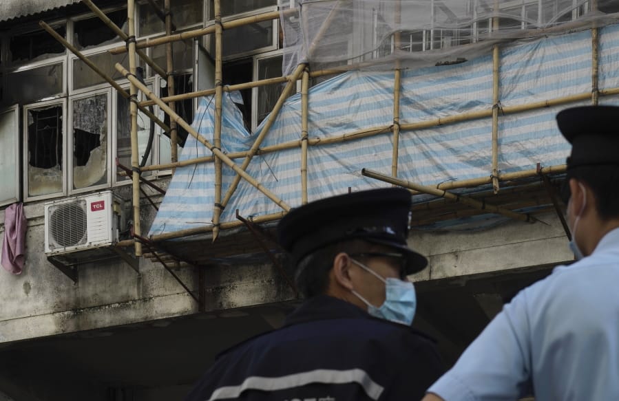 Police officers stand guard at a fire site, top left with broken windows, in Hong Kong Monday, Nov. 16, 2020. City authorities said a fire in a crowded residential district in Hong Kong has &quot;caused a number of deaths and injuries&quot;.
