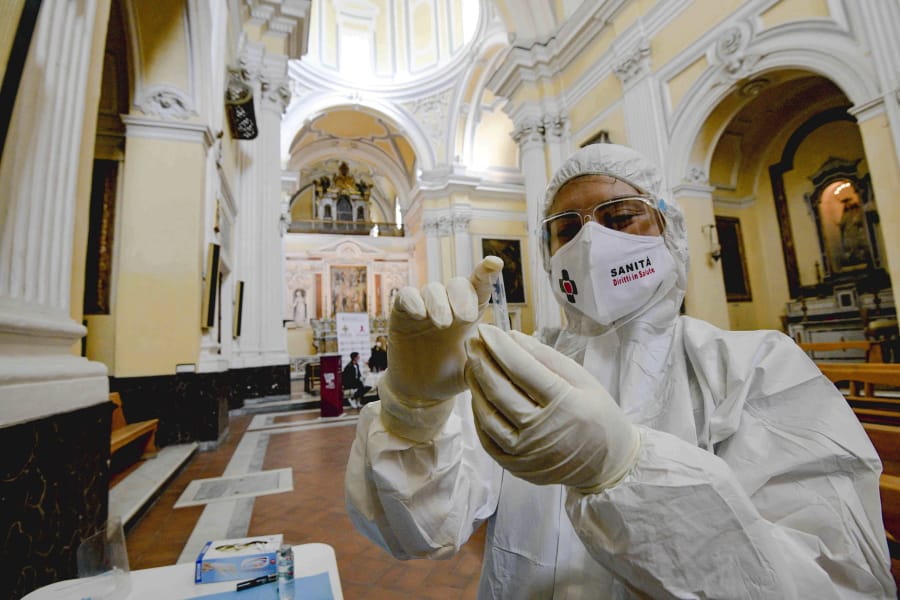 A medical operator prepares to perform COVID-19 test swabs in the Church of San Severo Outside the Walls, in the heart of Naples, Italy, Wednesday, Nov. 18, 2020. An initiative of &quot;Sanita&#039; Diritti Salute&quot; association and the San Gennaro Foundation, aimed at helping those who cannot afford the cost of a private test, also allows, in the best tradition of Naples, those who want to pay 18 euros for a &quot;suspended swab&quot;, to be taken by somebody else, exactly as it happens for the famous Neapolitan &quot;suspended coffee&quot;.
