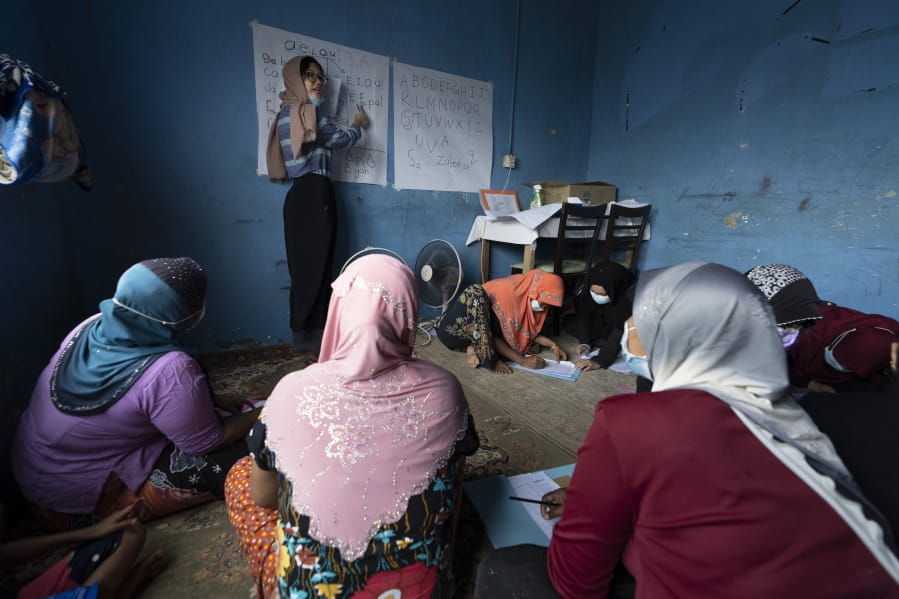 A volunteer teacher gives a basic English lesson to a minority Muslim Rohingya refugees at a slum on the outskirts of Kuala Lumpur, Malaysia, on Oct. 11, 2020. Refugee women in Malaysia, some in their late 50s, are learning to read and write for the first time. The classes outside Kuala Lumpur are offered by the Women for Refugees group, which was formed in September by two law students to help illiterate migrant women integrate into the local community and empower them to be more than just passive wives.
