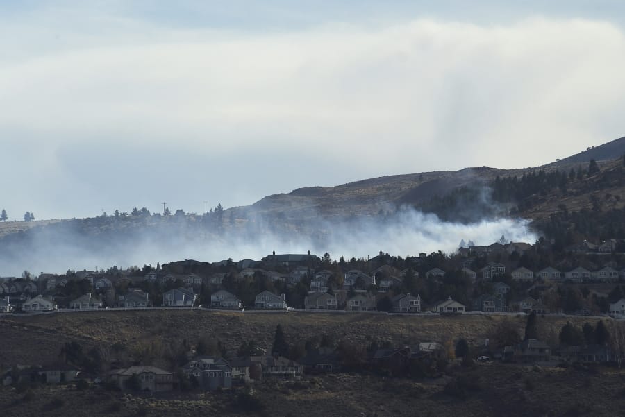 A fire is seen burning in the Caughlin Ranch area of Reno, Nev., on Tuesday, Nov. 17, 2020. Firefighters are battling a wildfire in southwest Reno that is threatening some homes in dangerously high winds. Dozens of residences were being evacuated on the edge of the Sierra foothills.