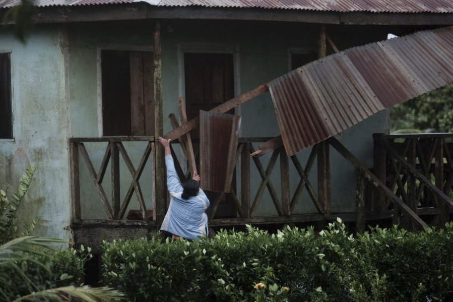 A woman works to recover the part of roof damaged by Hurricane Eta in Wawa, Nicaragua, Tuesday, Nov. 3, 2020. Eta slammed into Nicaragua&#039;s Caribbean coast with potentially devastating winds Tuesday, while heavy rains thrown off by the Category 4 storm already were causing rivers to overflow across Central America.