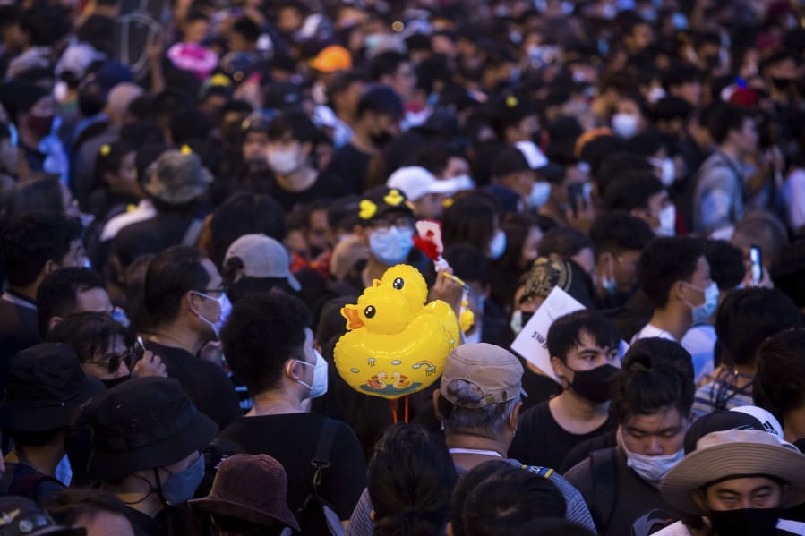 Inflatable yellow ducks, which have become a good-humored symbol of resistance during anti-government rallies, are held by a protester during a rally Wednesday, Nov. 25, 2020 in Bangkok, Thailand. Pro-democracy demonstrators in Thailand on Wednesday again took to the streets of the capital, even as the government escalated its legal battle against them, reviving the use of a harsh law against defaming the monarchy.