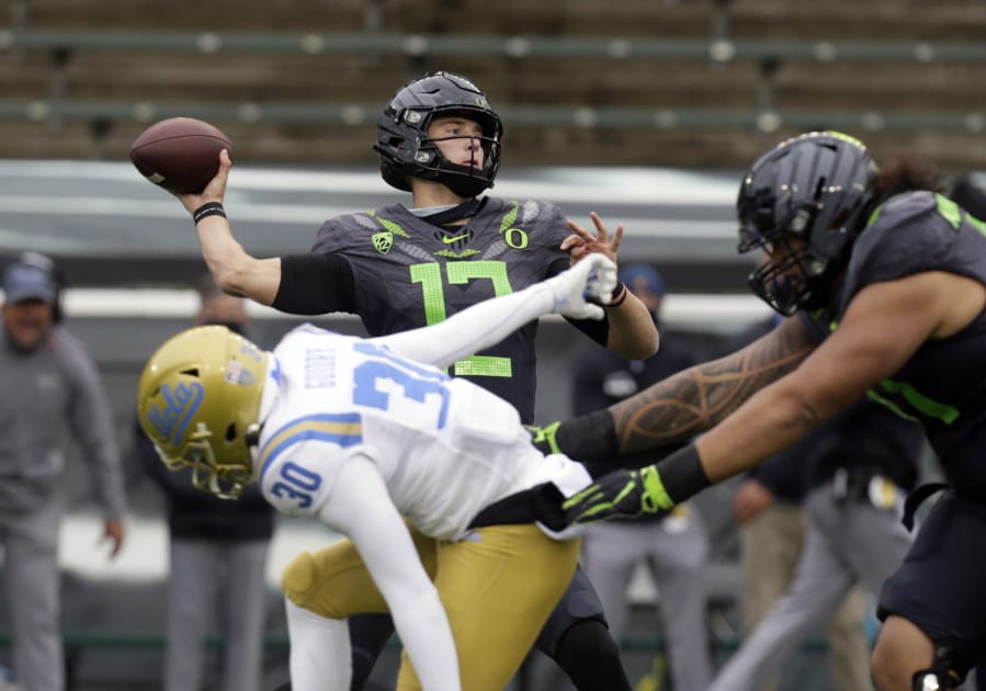 Oregon&#039;s Tyler Shough throws down field under pressure from UCLA&#039;s Elisha Guidry during the second quarter of an NCAA college football game Saturday, Nov. 21, 2020, in Eugene, Ore.