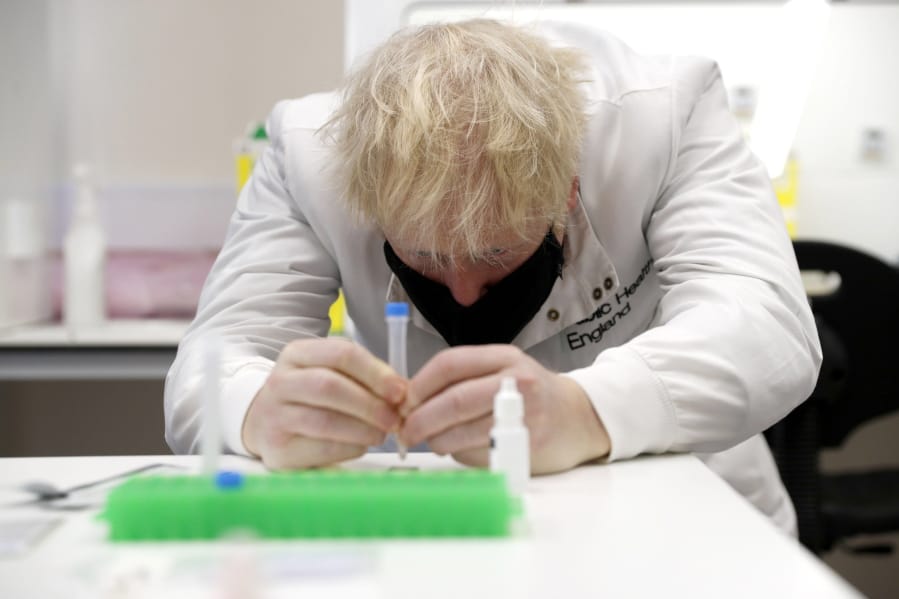 Britain&#039;s Prime Minister Boris Johnson, wearing a mask because of the coronavirus,  has a close look at a sample at the Lateral Flow Testing Laboratory during a visit to the Public Health England site at Porton Down science park near Salisbury, southern England, on Friday Nov. 27, 2020.