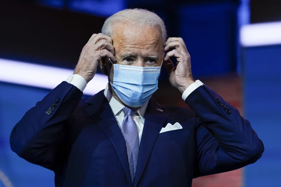 FILE - In this Nov. 24, 2020, file photo President-elect Joe Biden puts on his face mask after introducing nominees and appointees to key national security and foreign policy posts at The Queen theater in Wilmington, Del.