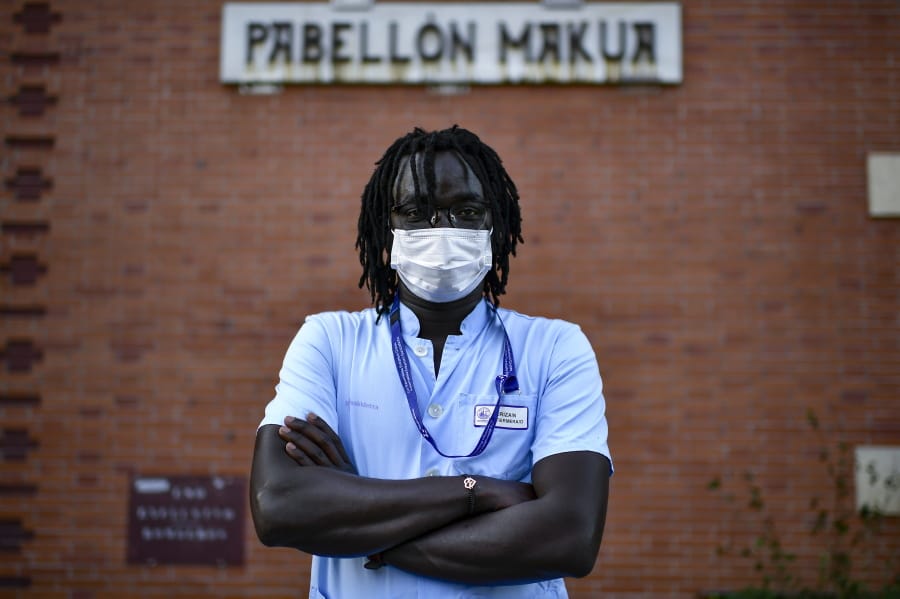 Mbaye Babacar Diouf, poses for a photo wearing his nurse&#039;s uniform, at Basurto hospital, in Bilbao, northern Spain, Wednesday, Nov. 18, 2020. Mbaye Babacar Diouf&#039;s life as a migrant in Europe took a turn for the better when he was adopted in Spain at the age of 28. That enabled him to pay his debts to human traffickers, study nursing and find a job at a Spanish hospital. Now he&#039;s giving back to the community. In a Bilbao hospital he cares for COVID-19 patients.