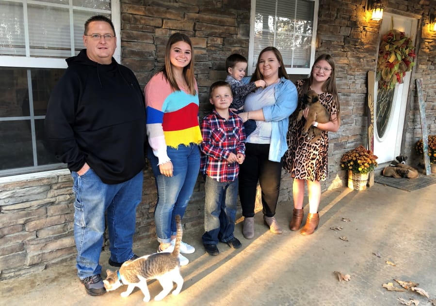 Keith Michael, left, poses with his children, from left, Jessica, Hunter, Houston, Sara and Holly, outside their home on Friday, Nov. 13, 2020, in Jonesboro, Ark. Among the victims of the coronavirus is Michael&#039;s wife, fourth-grade Arkansas teacher Susanne Michael, who died less than three months after celebrating the adoption of three of the children.
