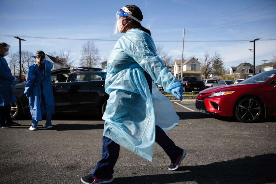 FILE - In this Nov. 19, 2020, file photo, a nurse carries a COVID-19 test back for processing at PrimaryOne Health in Columbus, Ohio. The surge of coronavirus is taking an increasingly grim toll across the United States, even as of a vaccine appears close at hand. (Joshua A.