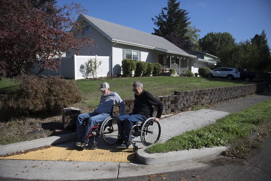 Vancouver resident Chuck Frayer, left, and friend John Williams show how they use a modern curb cut designed to make sidewalks accessible to people with all kinds of disabilities.
