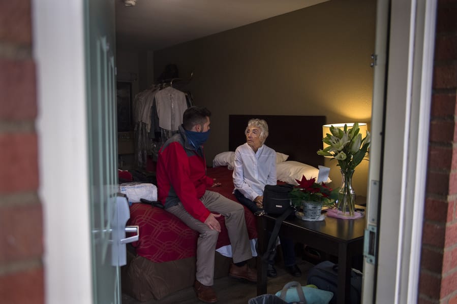 Andrew Stewart chats with Loretta Shaw at her downtown motel room. After her rental home was sold, Shaw was forced to live in her car until Stewart and others helped her.