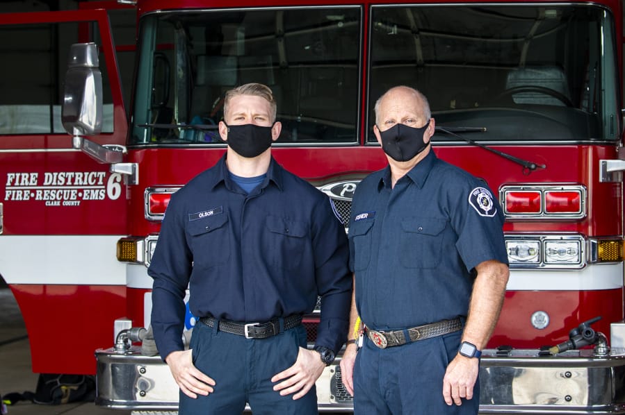 Firefighter and paramedic Max Olson, left, and firefighter and emergency medical technician Dave Fisher pose in front of a fire truck on Dec. 8 at Clark County Fire District 6 Station 61. They responded to the first reported COVID-19 case in the county.