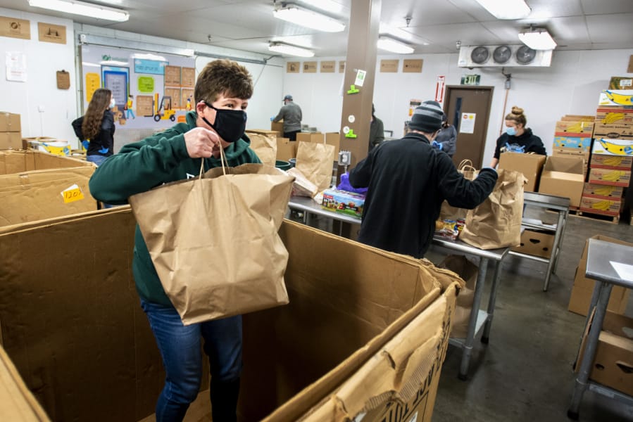 Volunteer Ray Thorne, who has volunteered at the food bank for close to two decades, helps gather food items out of a large box for others to sort on Tuesday at the Clark County Food Bank. The donations were from Saturday's Drive & Drop food drive, which in previous years was known as Walk & Knock.