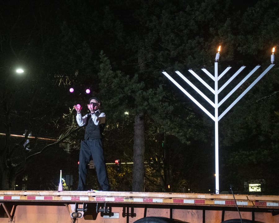 A performer from Circus Luminescence juggles in front of an audience at a drive-in menorah lighting Thursday night in a parking lot across the street from the Clark County Historical Museum.