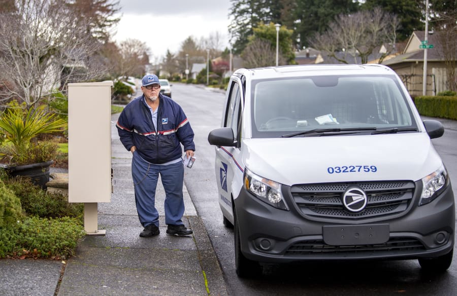 U.S. Postal Service mail carrier Cody Hershaw looks down the street as he gets back into his delivery car on a recent Thursday while on a route in the Cascade neighborhoods in Vancouver.