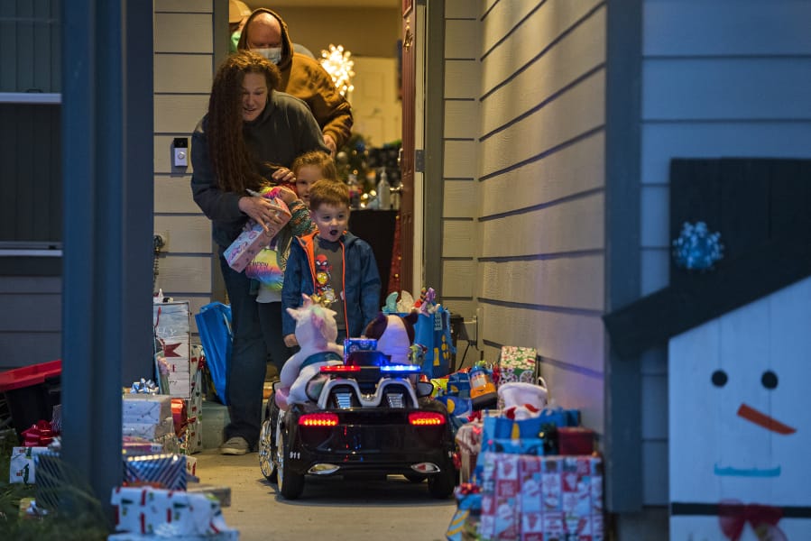 Kevin Hale, background in tan to front, of Longview joins his wife, Lindsay, his daughter, Annabelle, 6, and his son, Sawyer, 4, as they walk out to a porch full of donated gifts on Friday evening. Members of the Vancouver Police Department Domestic Violence Unit delivered the gifts to the family. Kevin Hale has been diagnosed with Stage 4 endocrine cancer, and his wife, Lindsay, works for the Clark County Prosecuting Attorney's Office as a victim advocate with the domestic violence unit.