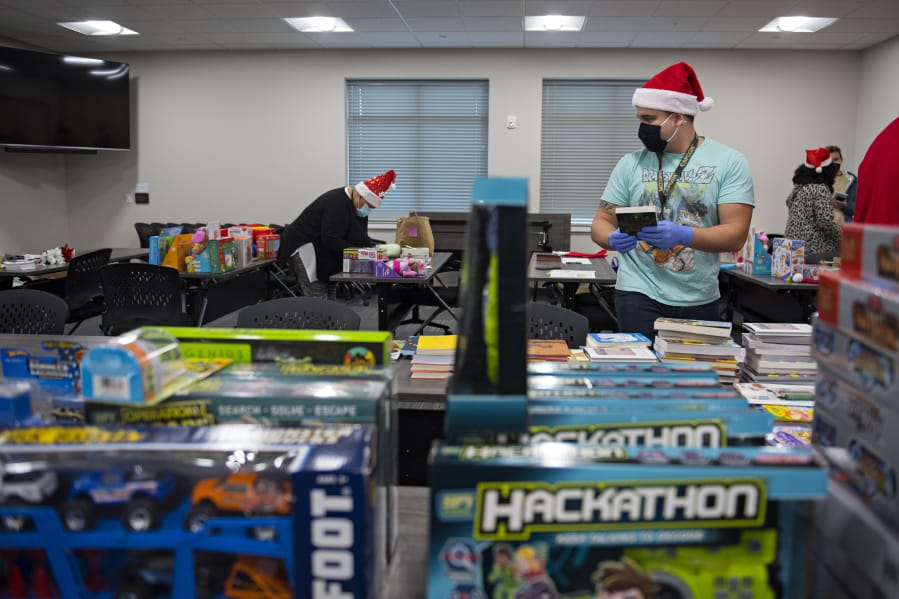 Damien Wheeler of Bridgeview Resource Center in Vancouver joins fellow helpers as he sorts through Christmas gifts for kids. The toy drive served about 150 local families during a year when many have lost jobs due to the COVID-19 pandemic.
