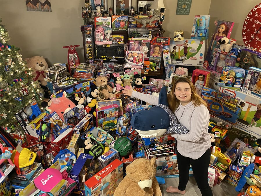 Madeline McMillen poses with some of the 728 toys donated by friends, family and businesses. &quot;I want children to have good Christmases and make sure they&#039;re still loved,&quot; the Prairie High School sophomore said.