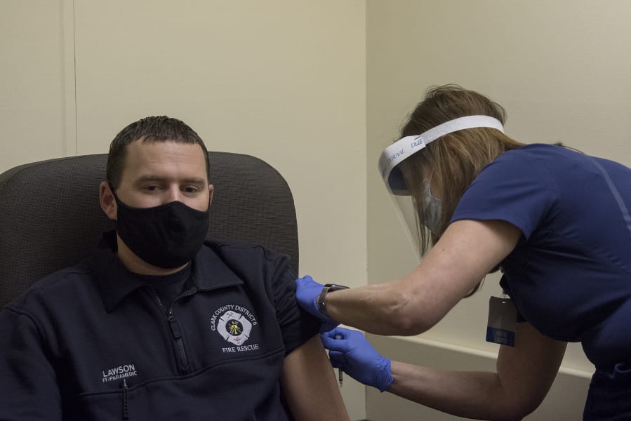 Firefighter and paramedic Josh Lawson, left, waits as system director Sara Williams applies a bandage after he received a COVID-19 vaccination at PeaceHealth Southwest Urgent Care in Vancouver. PeaceHealth has administered the vaccine to nearly 100 first responders from Clark and Cowlitz counties. The plan is to give roughly 200 first responders the first dose of the vaccine over the next couple weeks.