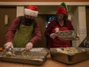 Steve Helland, left, and Marty Forsmann, both of Vancouver, load mashed potatoes and stuffing into to-go containers on Friday at a Christmas meal distribution event at WareHouse &#039;23.