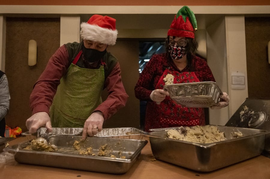 Steve Helland, left, and Marty Forsmann, both of Vancouver, load mashed potatoes and stuffing into to-go containers on Friday at a Christmas meal distribution event at WareHouse &#039;23.