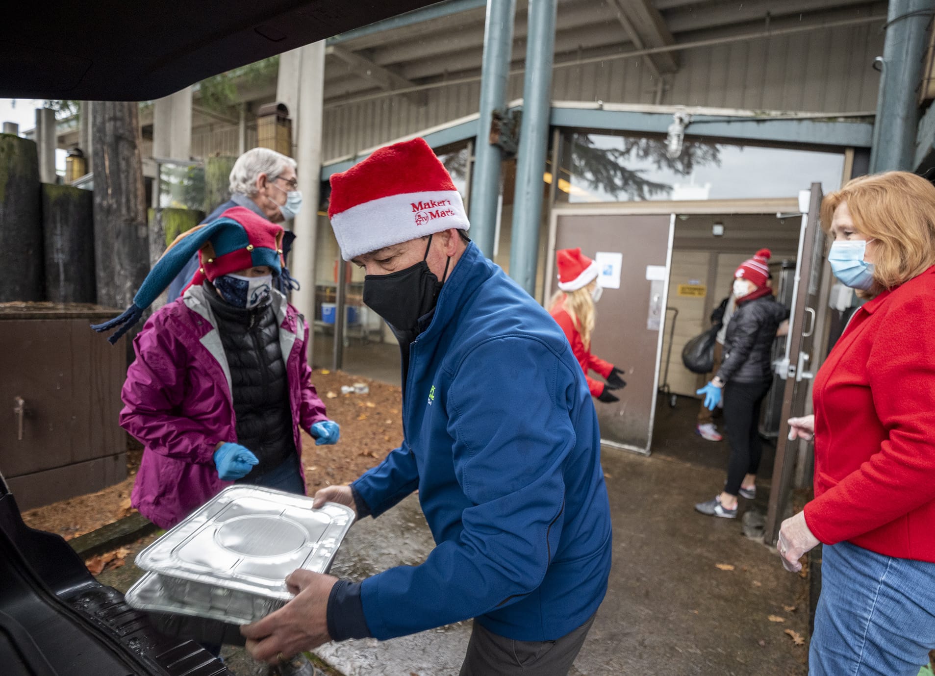 Doug Carr, center, of Battle Ground, and others load a vehicle that will deliver Christmas meals to a location in Vancouver on Friday at a Christmas meal distribution event at WareHouse '23.