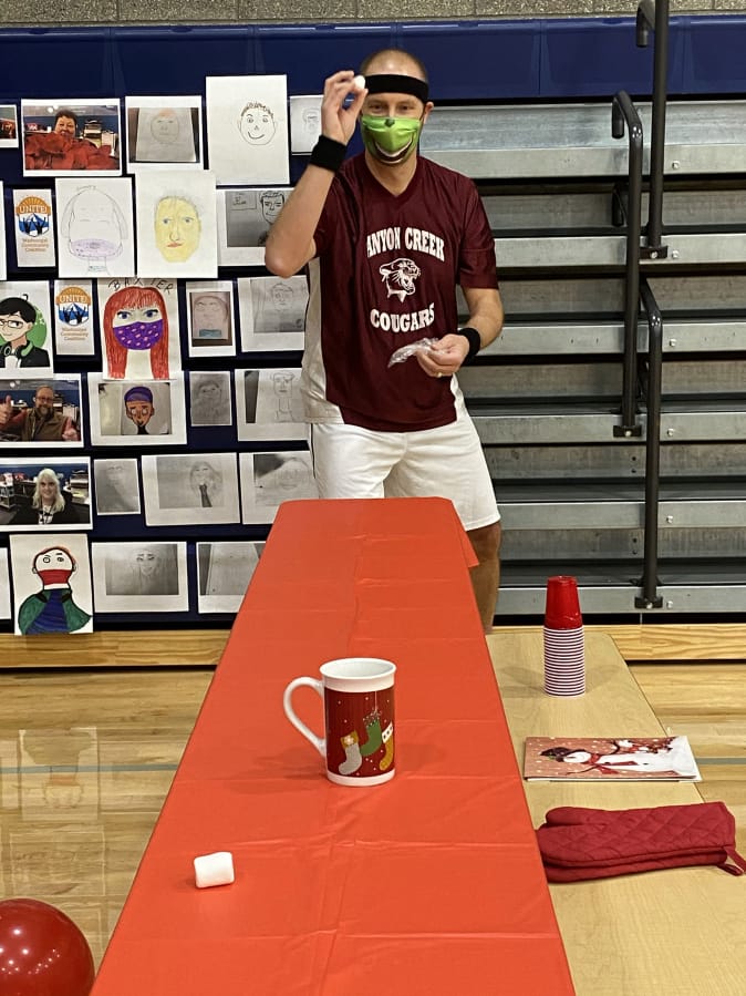 WASHOUGAL: Canyon Creek Middle School Principal Brian Amundson takes aim in the marshmallow toss challenge. Amundson and David Cooke, from Jemtegaard Middle School, battled against each other in a series of holiday-themed &quot;Minute to Win It&quot;-style competitions on Dec.